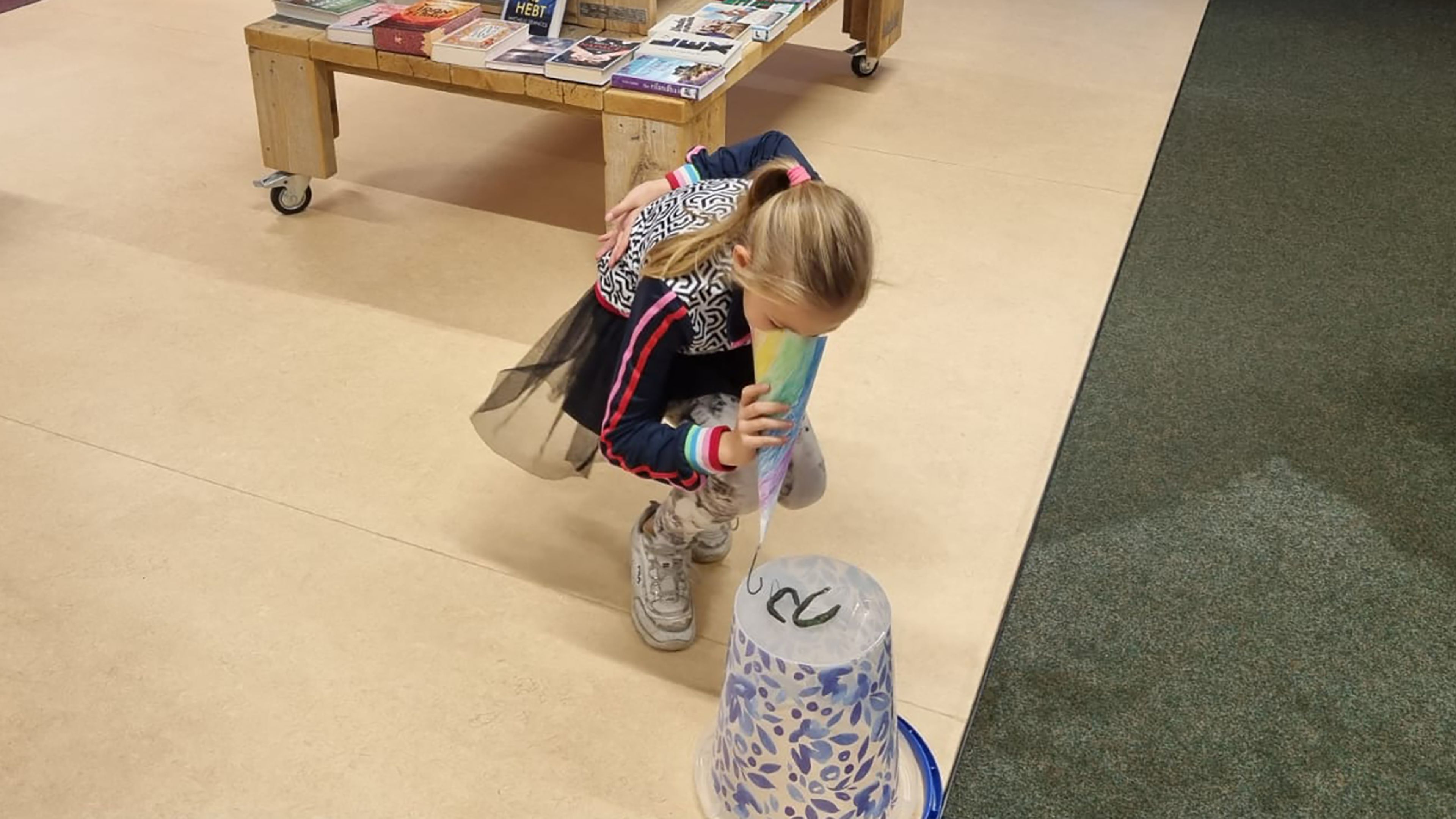Photo of a young girl holding a folded paper beak close to the nose