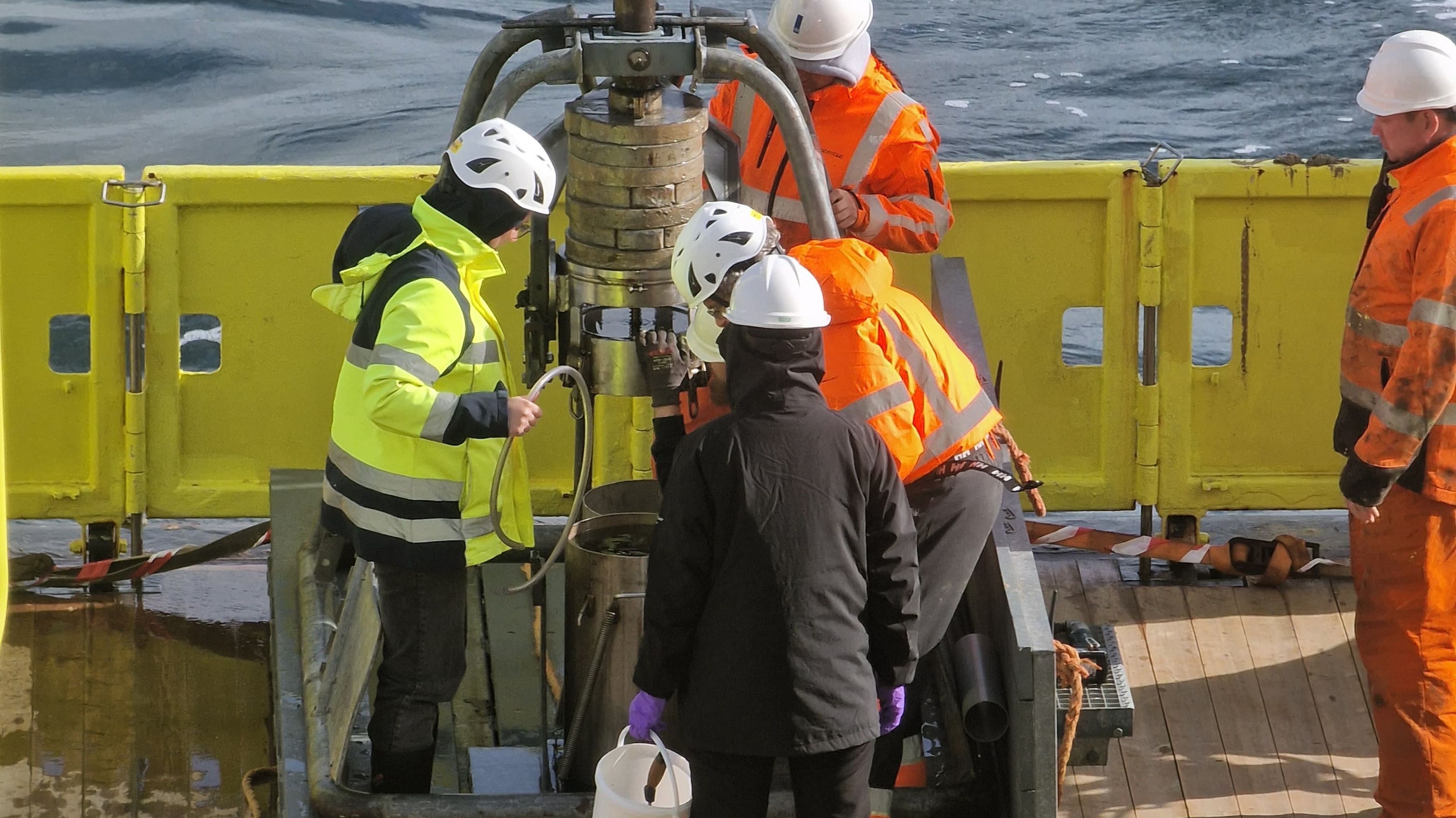 Photo of people on a research ship with a coring instrument